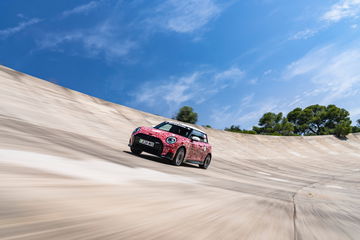 Vista dinámica del MINI JCW eléctrico en acción, deslizándose sobre arena.