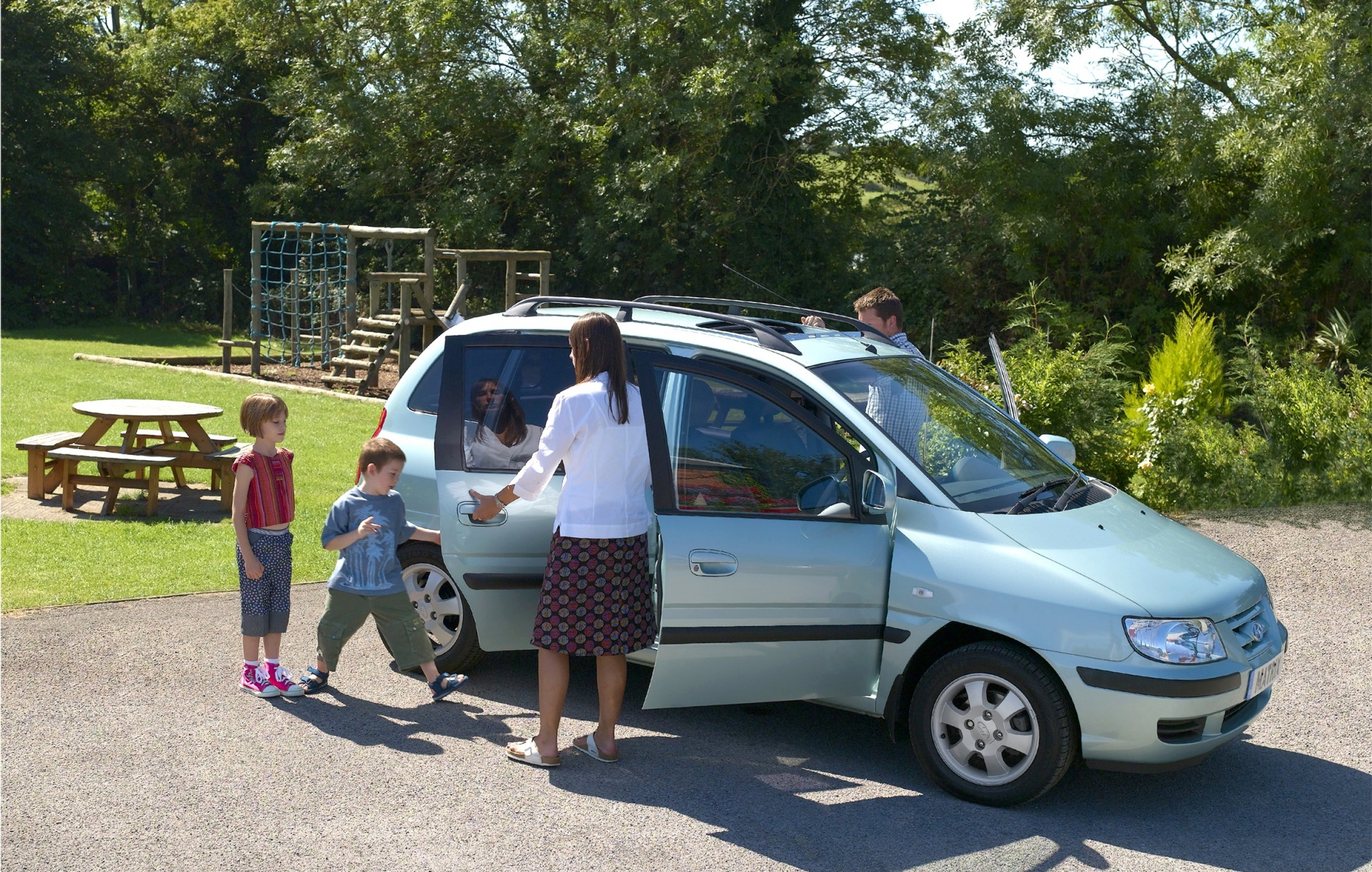 Una familia disfruta de un día de campo con su vehículo, ideal para viajes familiares.