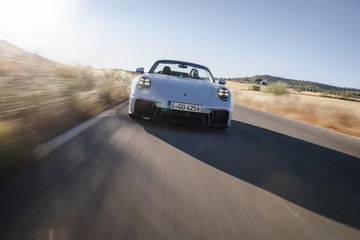 Vista dinámica del Porsche 911 GTS T-Hybrid, destacando su línea lateral y trasera.