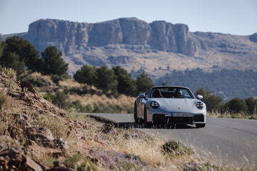 Vista lateral del Porsche 911 GTS T-Hybrid rodando en carretera montañosa