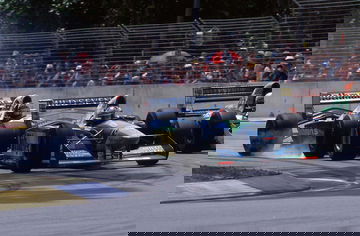 Vista lateral dinámica del Benetton B194 en acción en la pista