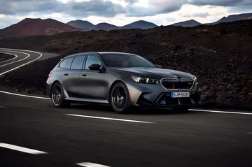 BMW M5 Touring 2025 mostrando su perfil lateral en movimiento.