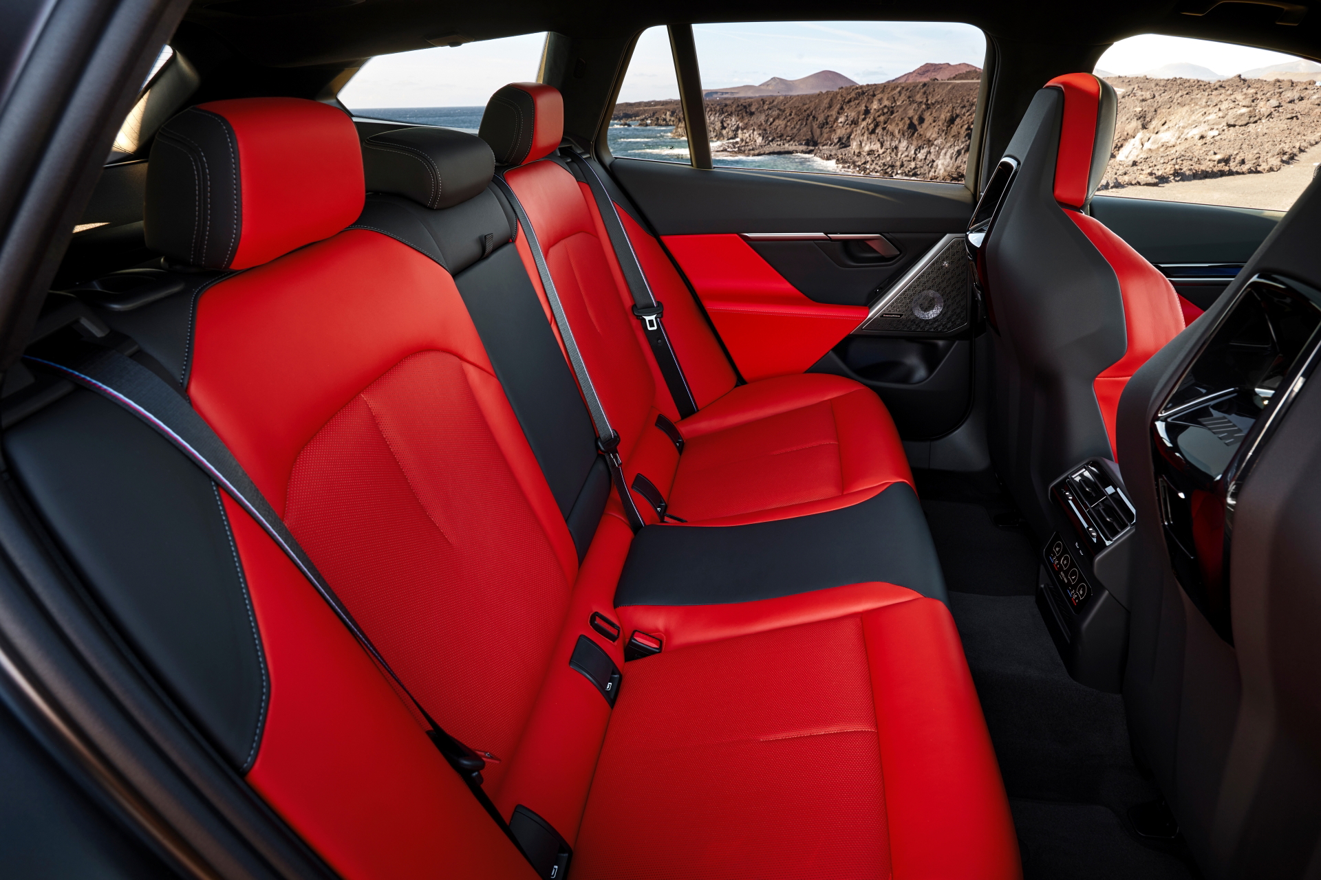 Vista lateral interior BMW M5 Touring, asientos rojos deportivos y acabados premium.