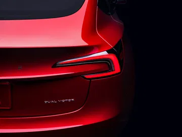 Vista trasera lateral enfocando la luz y diseño aerodinámico del Tesla Model 3.