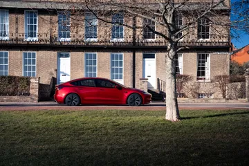 Tesla Model 3 en rojo destacando con su diseño lateral elegante y moderno.