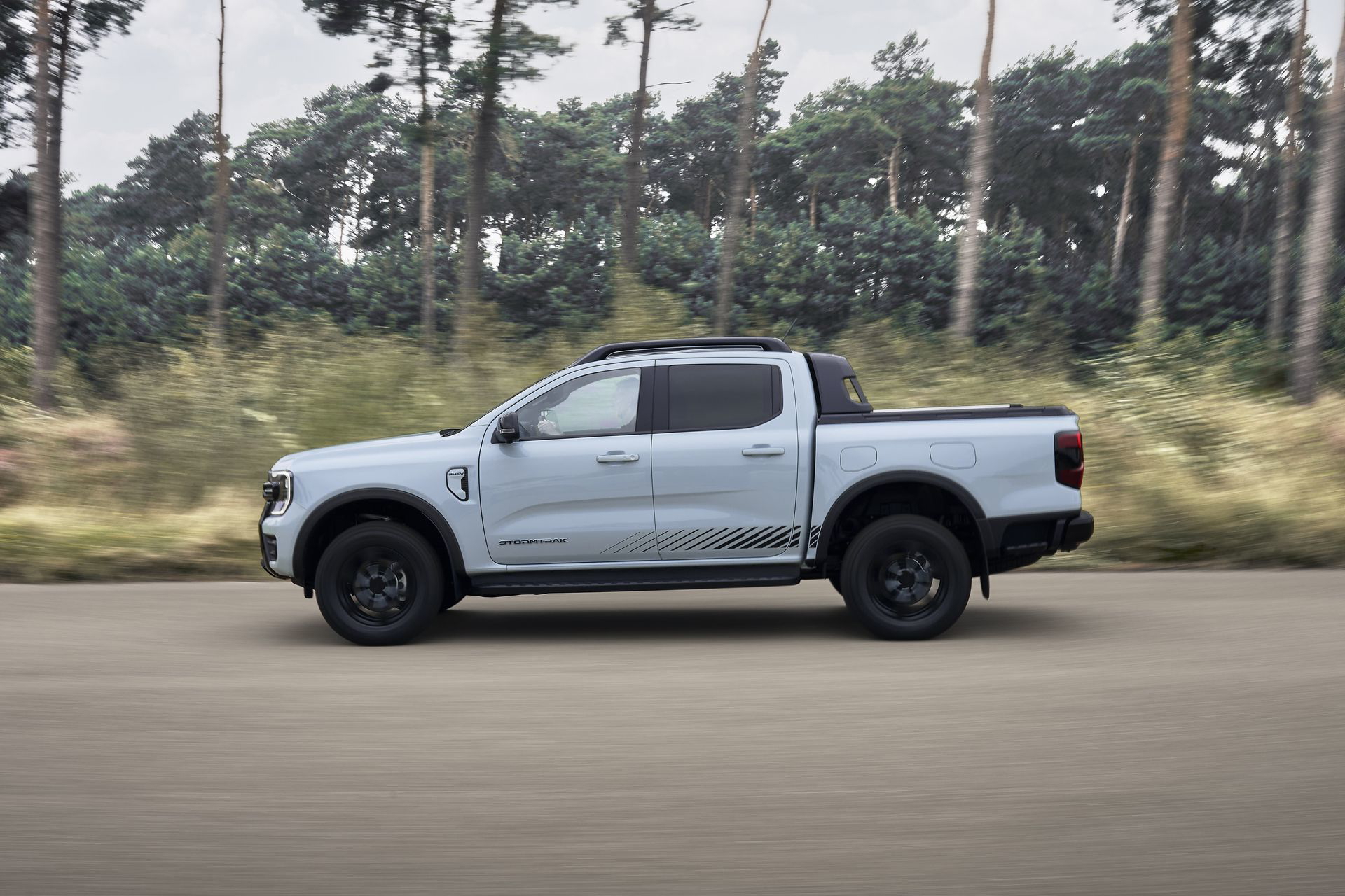 Vista lateral de la nueva Ford Ranger PHEV Stormtrak avanzando robusta y silenciosamente.