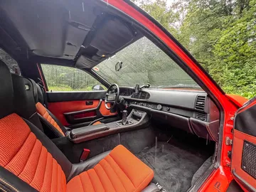 Vista del lujoso habitáculo del Porsche con asientos de cuero rojo y negro.