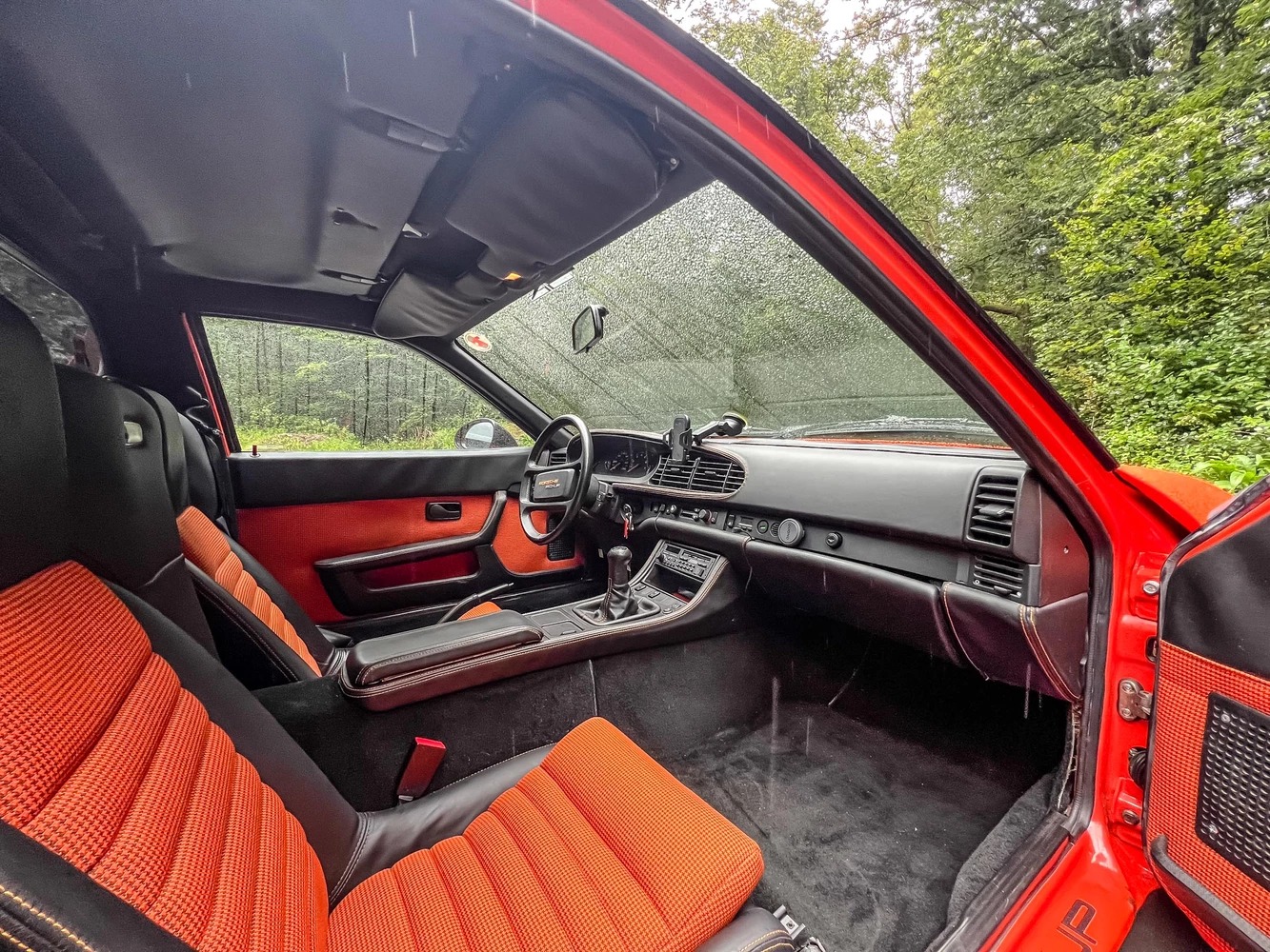 Vista del lujoso habitáculo del Porsche con asientos de cuero rojo y negro.