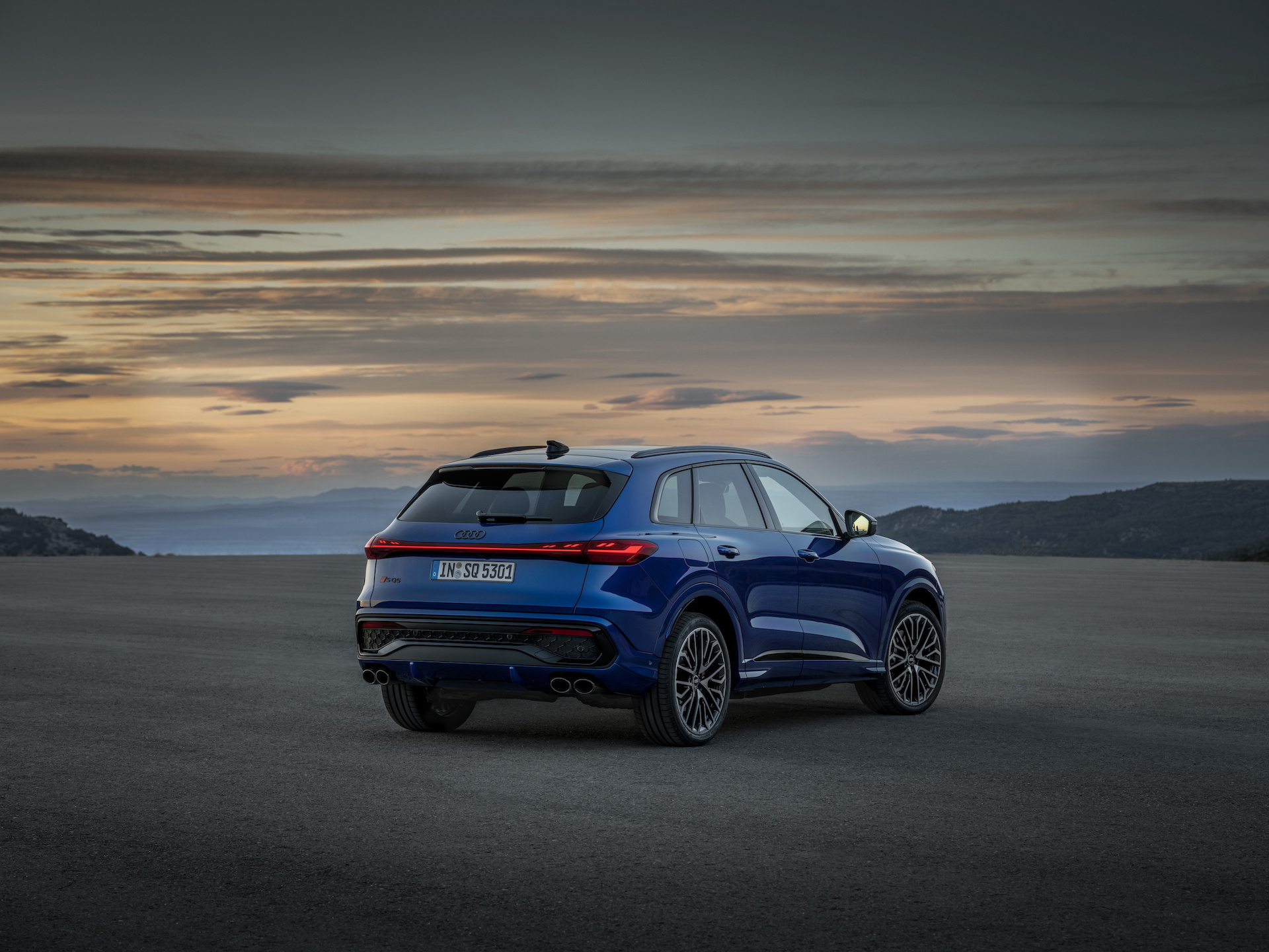 Vista trasera y lateral del nuevo Audi Q5 2025 en un entorno crepuscular.