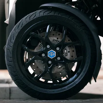 Vista cercana de la rueda delantera del Piaggio MP3 310, enfatizando su sólida estructura