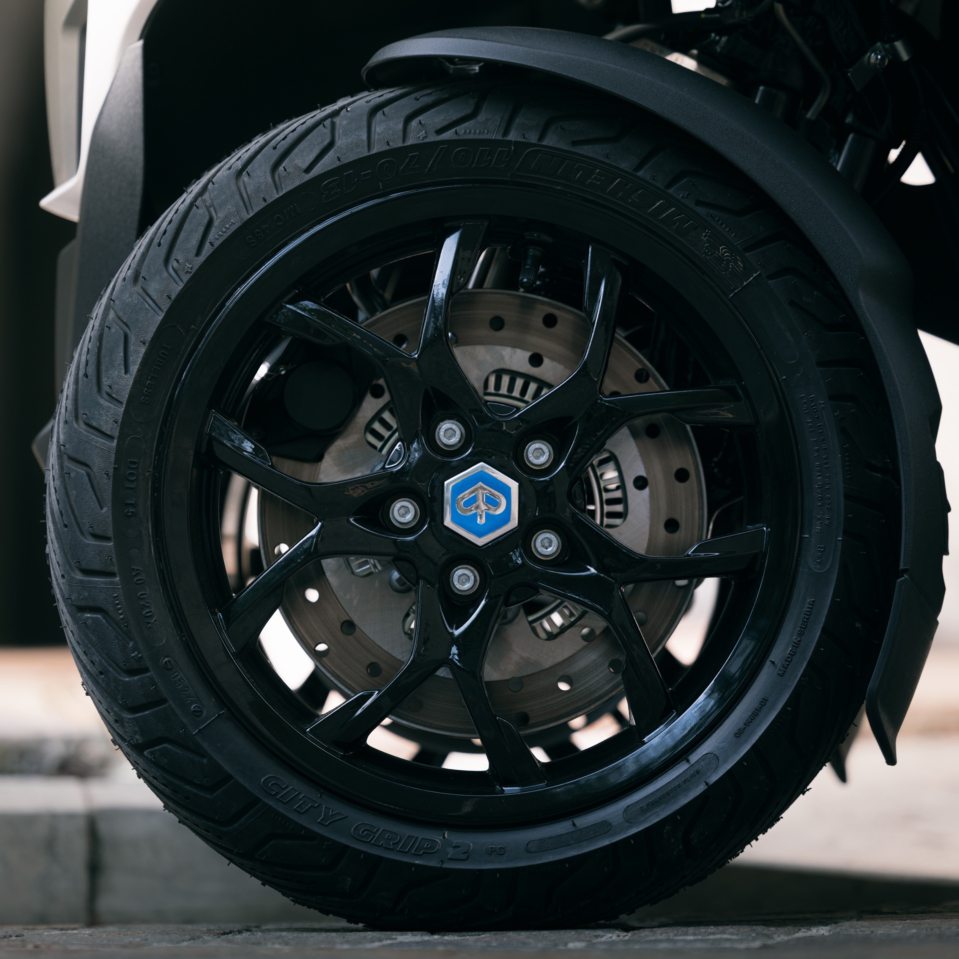 Vista cercana de la rueda delantera del Piaggio MP3 310, enfatizando su sólida estructura