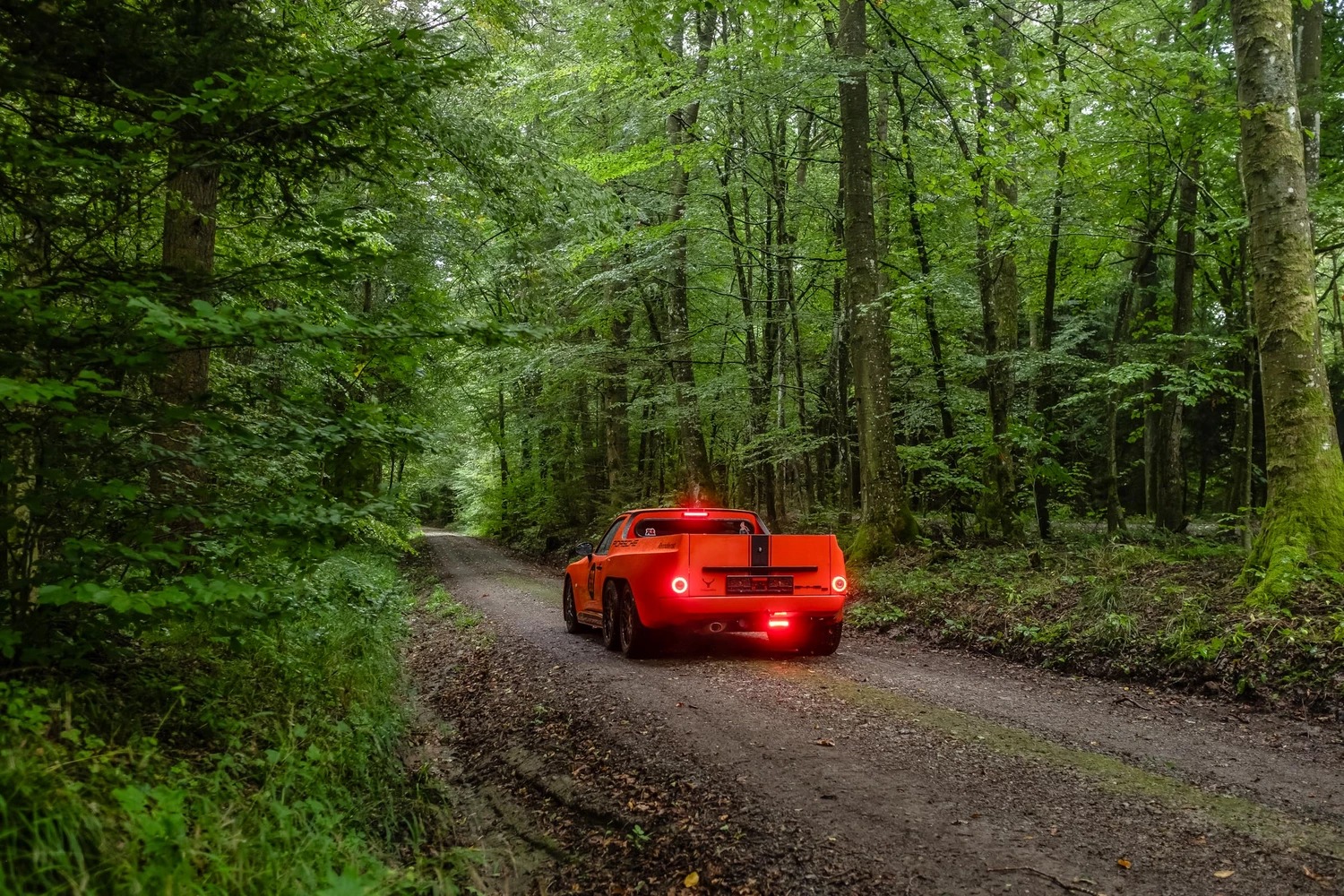 Una visión lateral de un Porsche 6x6 pickup en movimiento por un camino forestal.