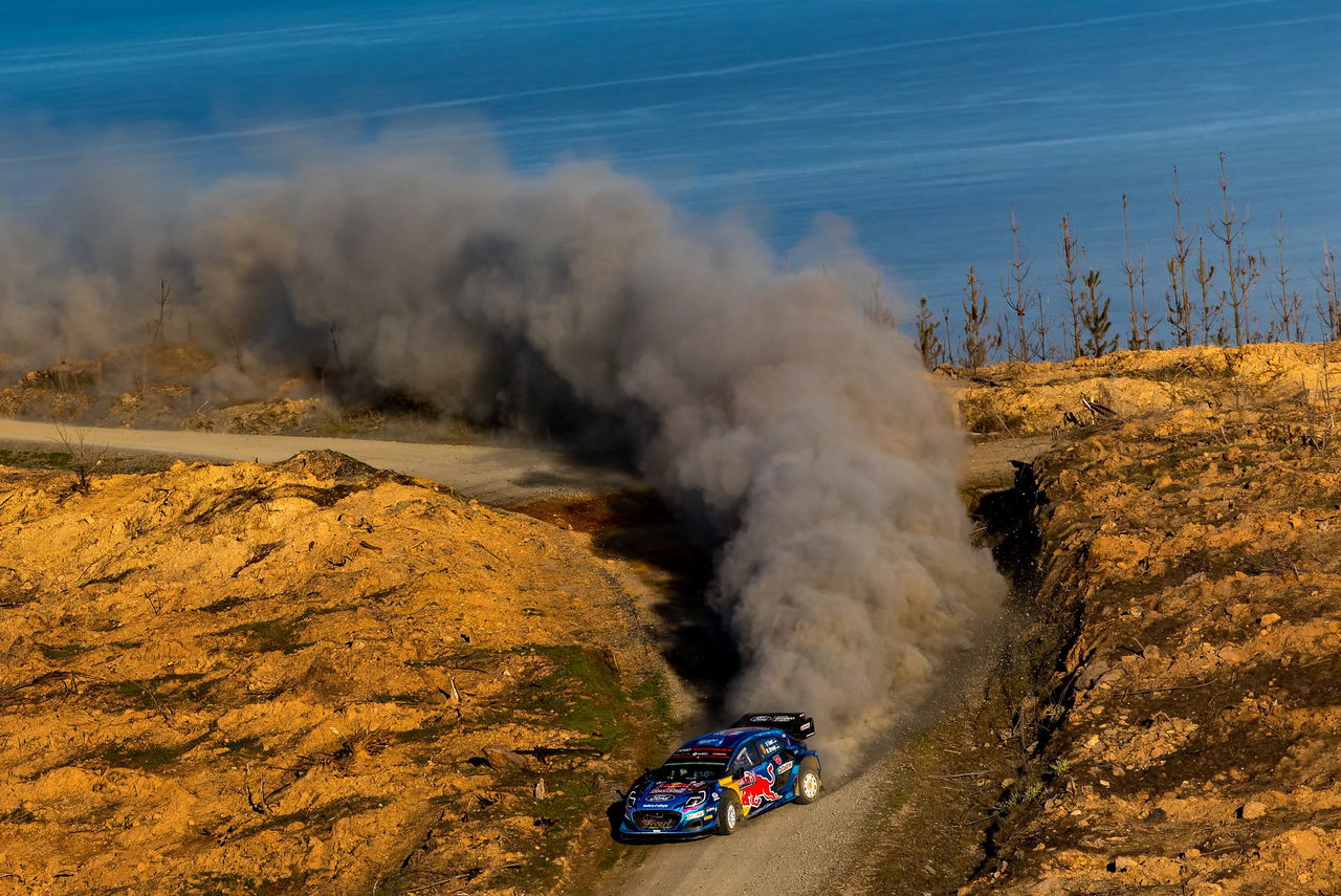 Vehículo de rally derrapando en curva con vista al paisaje chileno