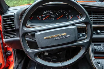 Volante deportivo con emblema de Porsche visible y mandos integrados.