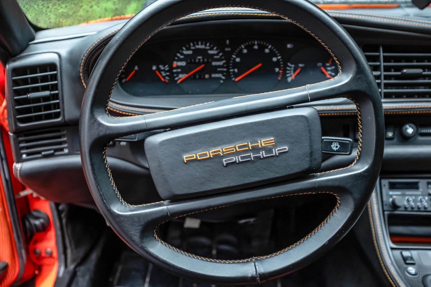 Volante deportivo con emblema de Porsche visible y mandos integrados.