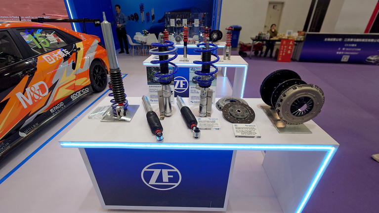 Vista de componentes de suspensi&oacute;n ZF con veh&iacute;culo de fondo.