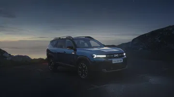 Vista delantera y lateral del Dacia Bigster 2025 en azul indigo, mostrando su robustez y diseño moderno.