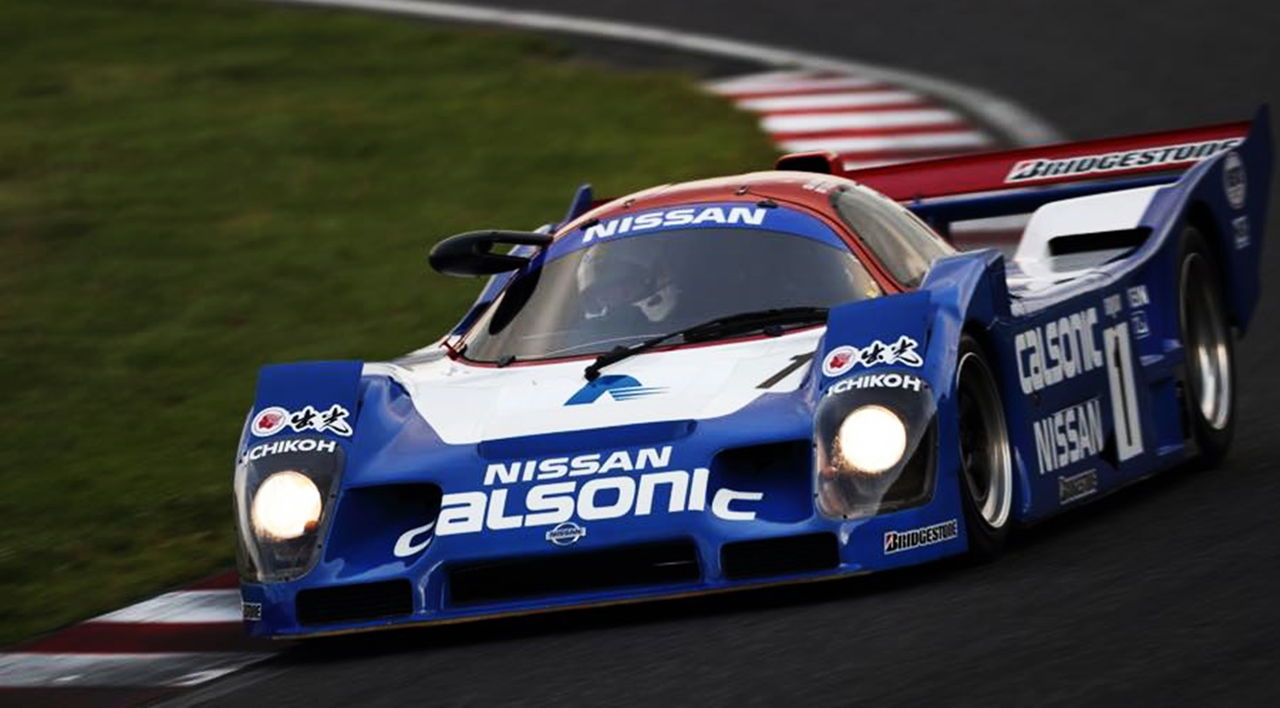 Vista lateral del prototipo de competición Nissan Calsonic en acción, con decoración icónica.