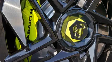 Vista cercana del emblema y llanta Abarth 600e con detalles deportivos.