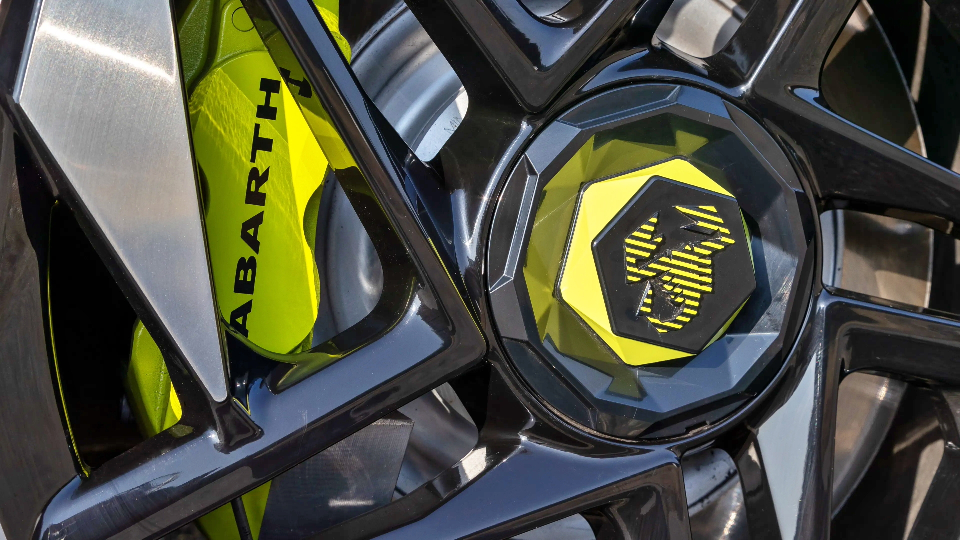 Vista cercana del emblema y llanta Abarth 600e con detalles deportivos.