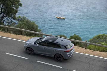 Vista lateral del Cupra Terramar en carretera con fondo marítimo.
