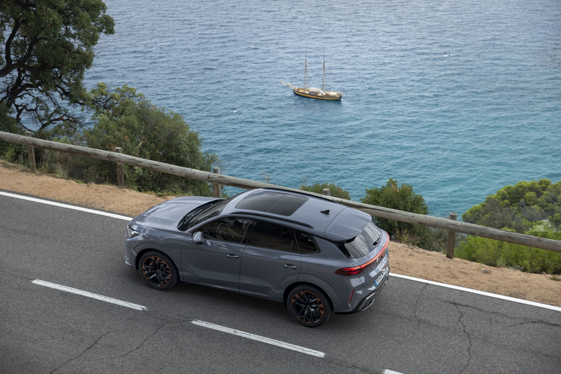Vista lateral del Cupra Terramar en carretera con fondo marítimo.