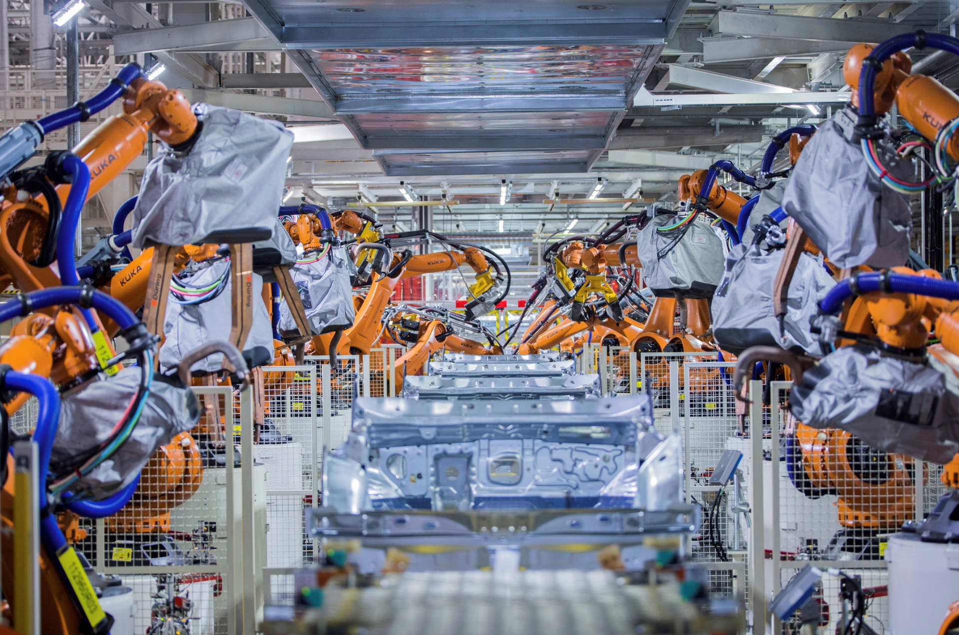 Línea de montaje de Volkswagen con robots y trabajadores ensamblando vehículos.