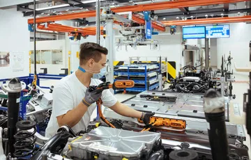 Trabajador en línea de montaje Volkswagen, enfoque en proceso de producción.