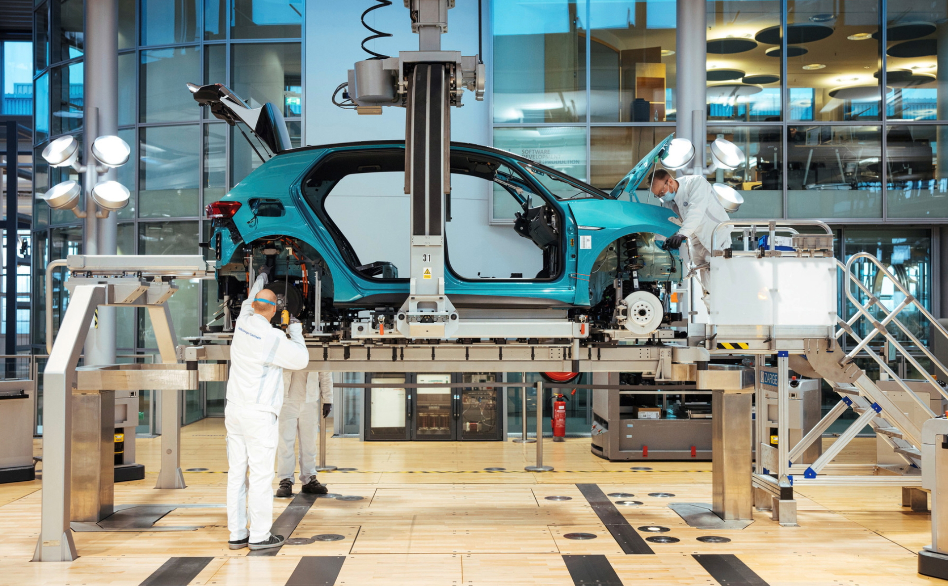 Empleados trabajando en Volkswagen, con carrocería de coche en ensamblaje.
