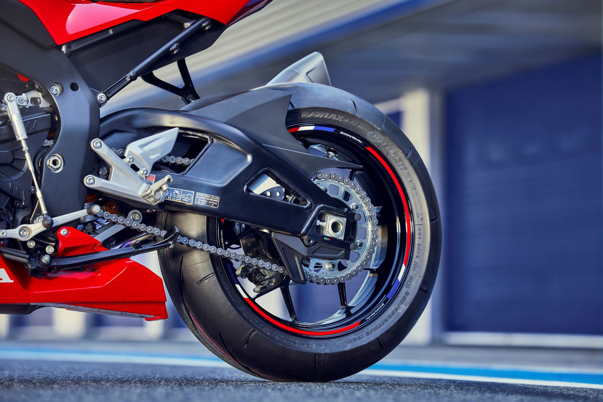 Vista trasera lateral de la Honda CBR1000RR-R Fireblade 2024, enfocando el neumático y el escape.