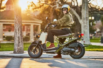 Honda Ruckus 2025 en un escenario urbano, destacando su diseño lateral.