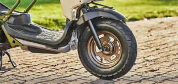 Vista lateral que muestra la rueda delantera y neumático robusto de la Honda Ruckus 2025.