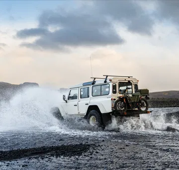 Vista dinámica del Land Rover Defender superando un terreno acuático con maestría