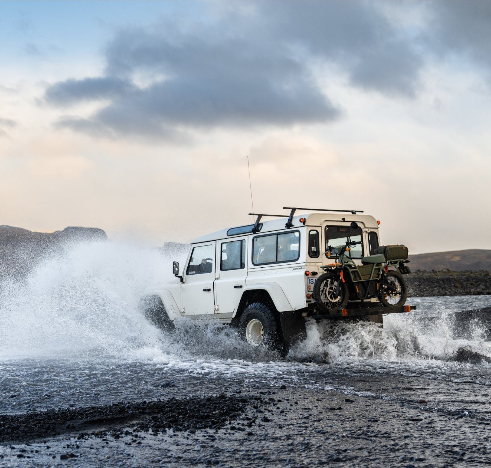 Vista dinámica del Land Rover Defender superando un terreno acuático con maestría