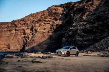 Vista lateral del Lexus NX 350h Overtrail posando en terreno escarpado.
