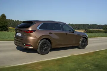 Vista dinámica lateral del Mazda CX-80, resaltando su diseño y proporciones.