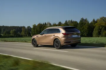 Vista lateral dinámica del Mazda CX-80, destacando su línea y diseño.