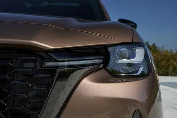 Vista en detalle de la parte frontal del Mazda CX-80 2025, destacando diseño agresivo y moderno.