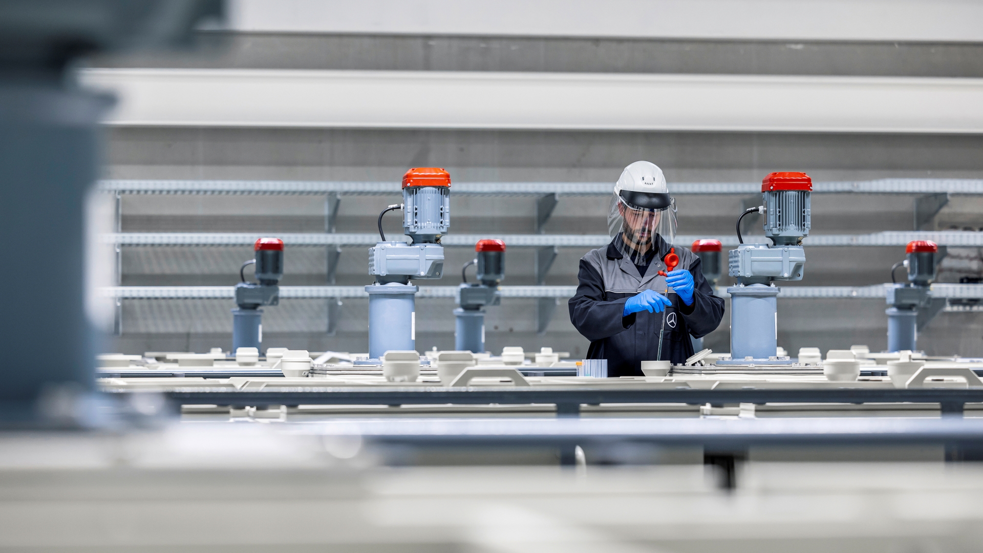 Trabajador inspeccionando componentes de baterías en planta de reciclaje.