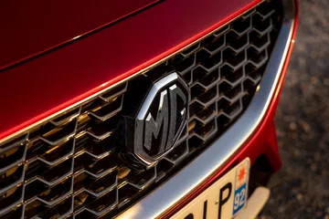 Vista cercana del emblema MG en la parrilla delantera del SUV MG ZS.