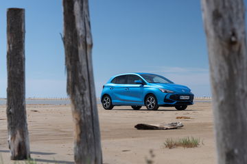 Vista lateral MG3, destacando su diseño y color vibrante a la orilla de la playa.