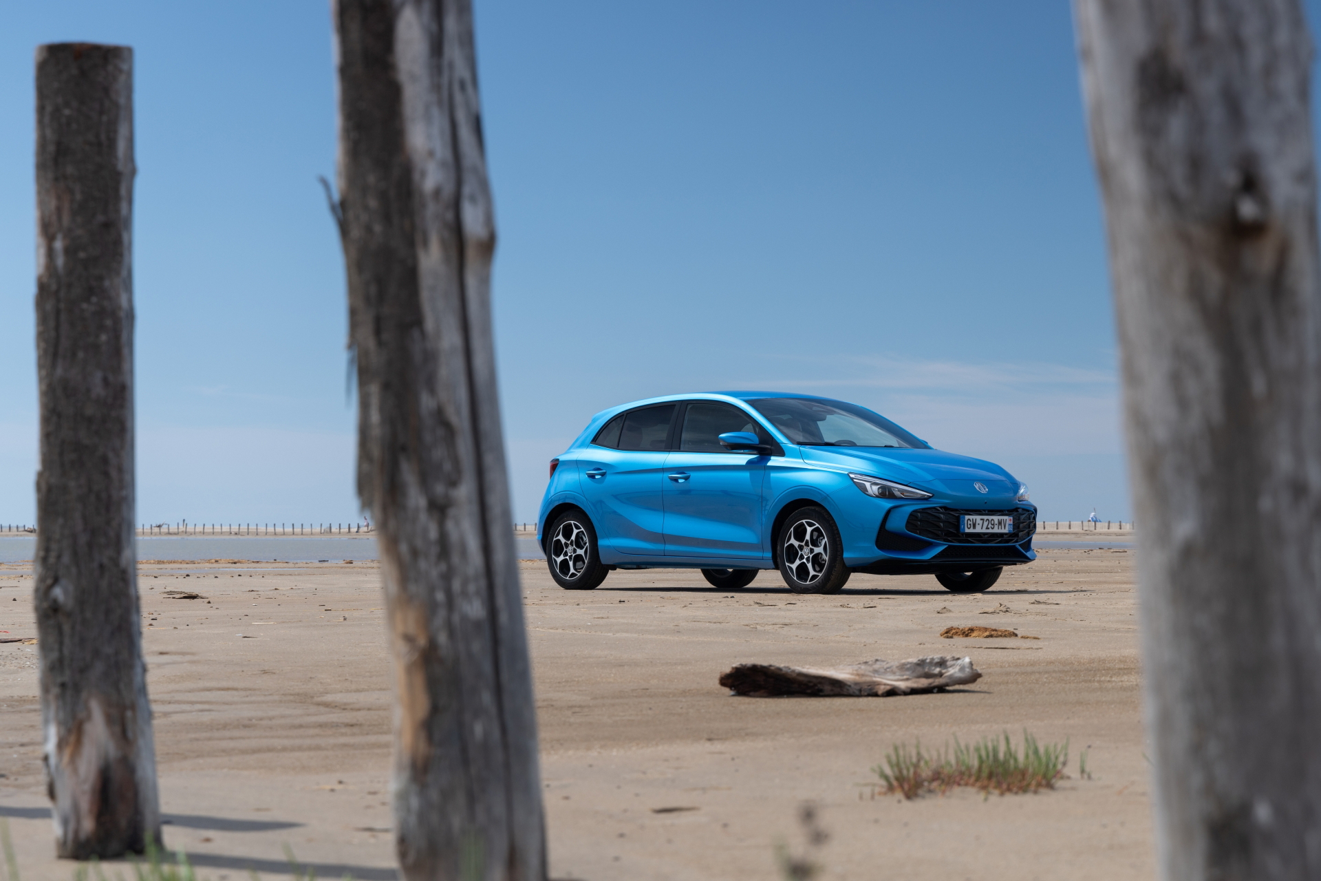 Vista lateral MG3, destacando su diseño y color vibrante a la orilla de la playa.