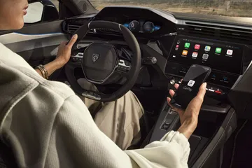 Vista del puesto de conducción del Peugeot e-408 con énfasis en su volante e instrumentación digital.