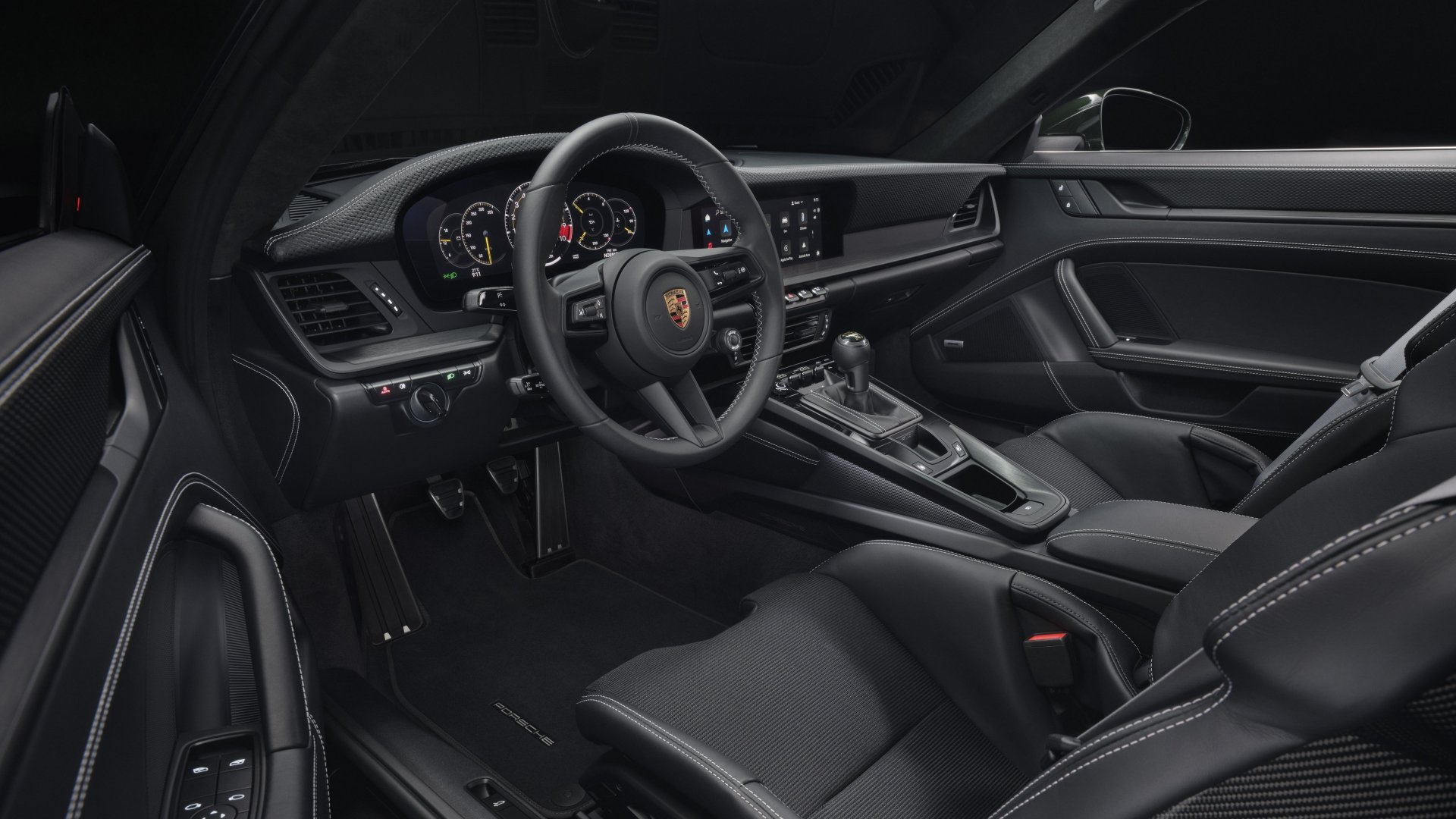Cabina del Porsche 911 GT3 992 con enfoque en volante y consola central.