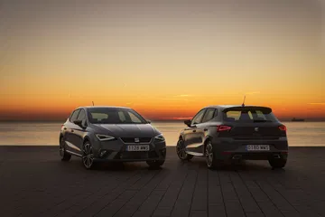 Dos SEAT Ibiza perfilados frente a la puesta de sol, evocando estilo y tradición.