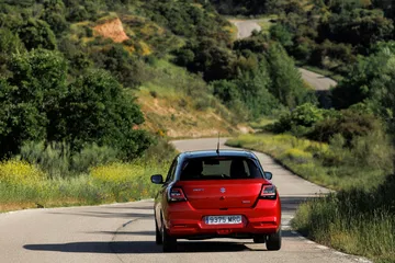 Vista dinámica del Suzuki Swift 2024 transitando por un entorno natural.