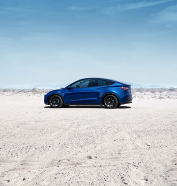 Vista lateral del Tesla Model Y en un entorno desértico, resaltando su diseño aerodinámico y líneas modernas.