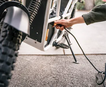 Primer plano de la bicicleta eléctrica UBCO 2x2 enfocando la suspensión y caballete.