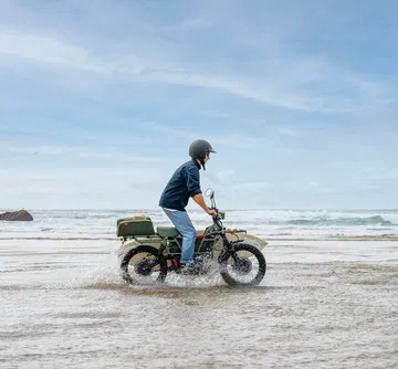 Vista lateral de la UBCO 2x2, una moto eléctrica todoterreno con diseño utilitario.