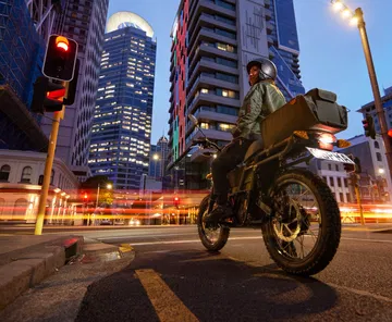 Moto eléctrica UBCO 2x2 capturada de perfil en un entorno urbano nocturno.